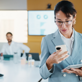 Woman looking at her phone while walking out of a meeting, representing decision-making during the M&A process