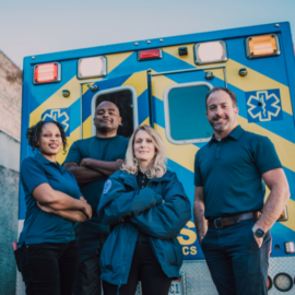 Team of EMS and ambulance workers in front of ambulance.